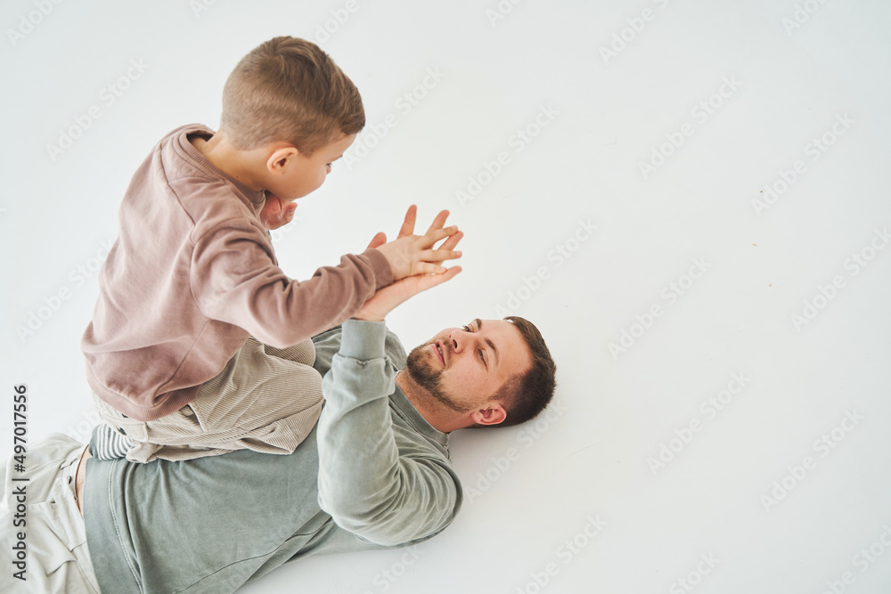 Father and son have fun and fool around together on white background. Child laughs with dad. Fatherhood. Child care.