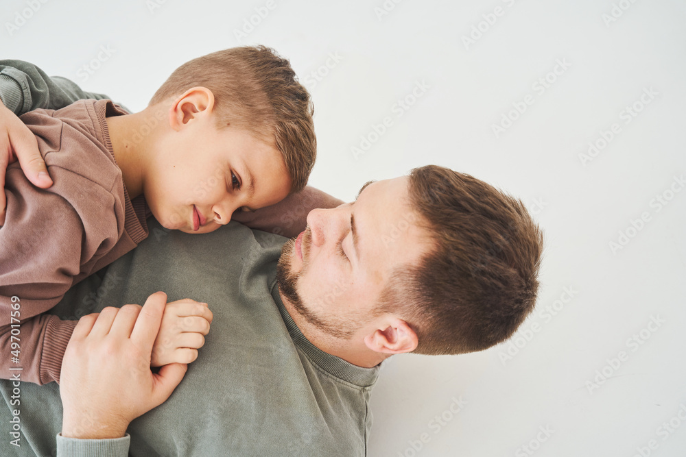 The son lies on the shoulder of his father. Dad hugs his child and smiles. Child care. The son lies on the shoulder of his father. Dad hugs his child and smiles. Child care.