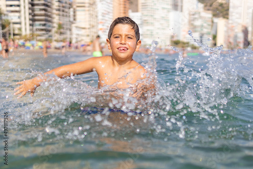 Funny kid spalshing water on an urban beach