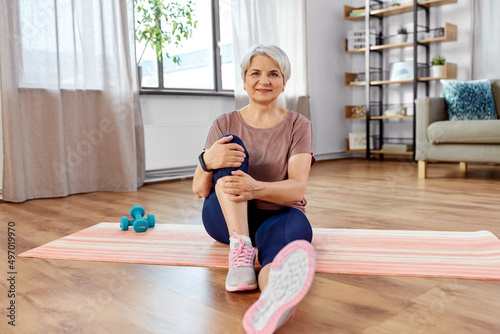 sport, fitness and healthy lifestyle concept - smiling senior woman exercising on mat at home