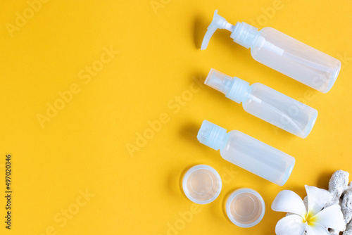 Set of empty travel bottles on yellow background, top view, copy space. A set of cosmetic bottles to carry in the baggage of the aircraft.