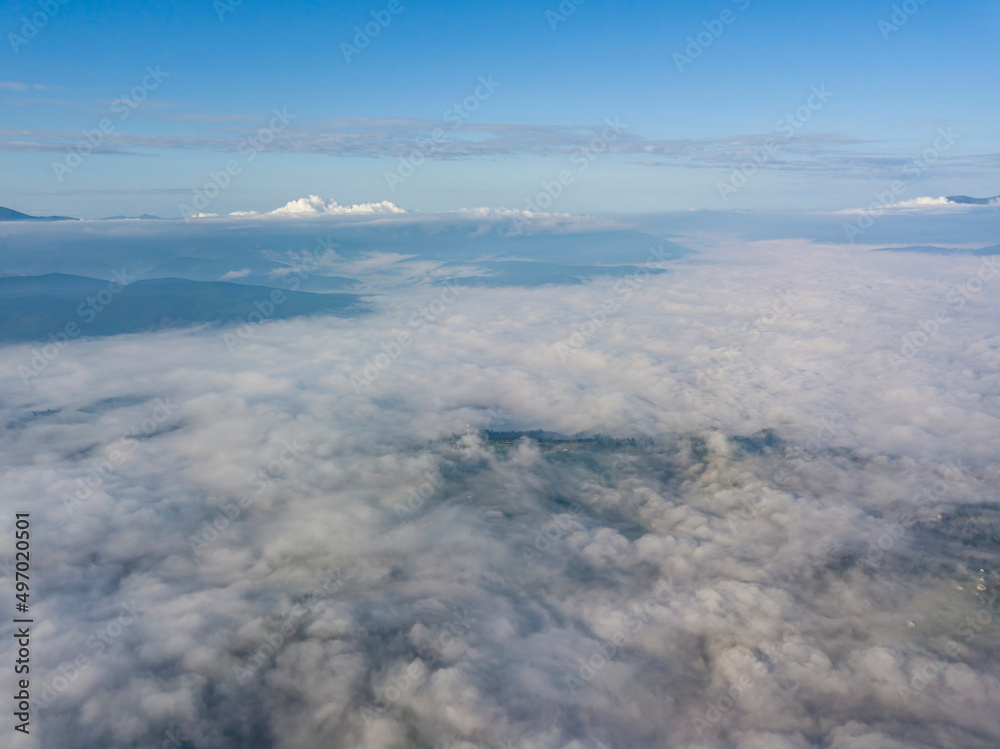 High flight above the clouds in the mountains. Aerial drone view.