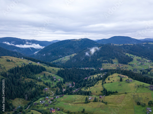 Green slopes of Ukrainian Carpathian mountains in summer. Cloudy morning  low clouds. Aerial drone view.