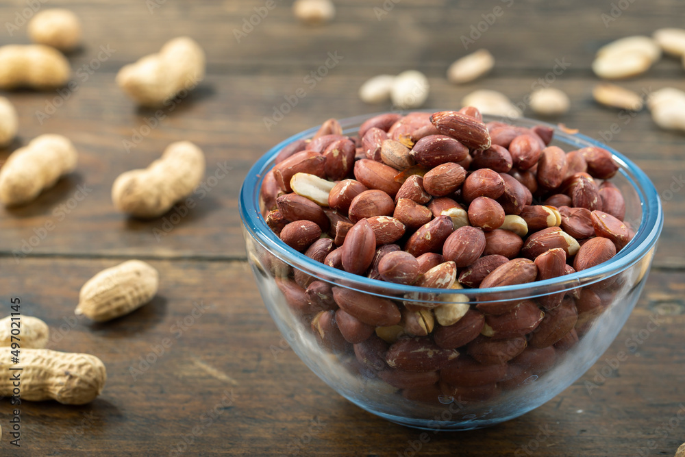 Peanuts in their husks in a glass bowl and peanuts in their skins are