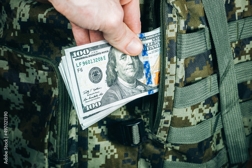Принти на полотні Man is putting in a military backpack dollars