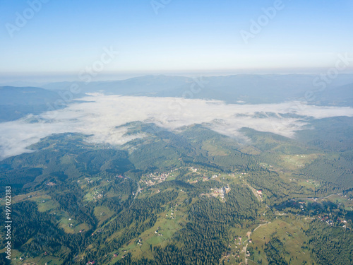 High flight in the mountains of the Ukrainian Carpathians. Fog in the valley. Aerial drone view. © Sergey
