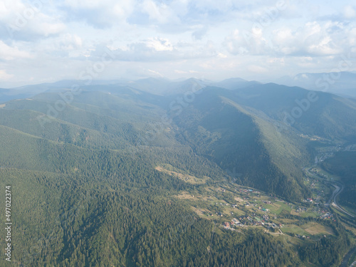 Green slopes of Ukrainian Carpathian mountains in summer. Cloudy day, low clouds. Aerial drone view. © Sergey