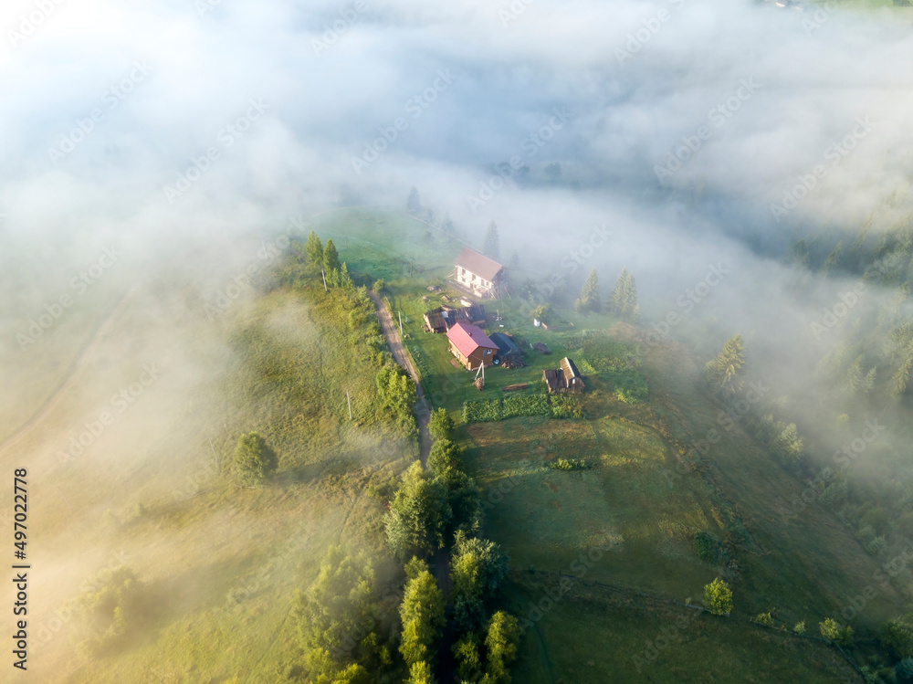 Fototapeta premium Mountain settlement in the Ukrainian Carpathians in the morning mist. Aerial drone view.