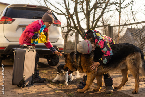 two little girls with the flag of ukraine, suitcase, dogs. Ukraine war migration. Collection of things in a suitcase. Flag of Ukraine, help. Krizin, military conflict.