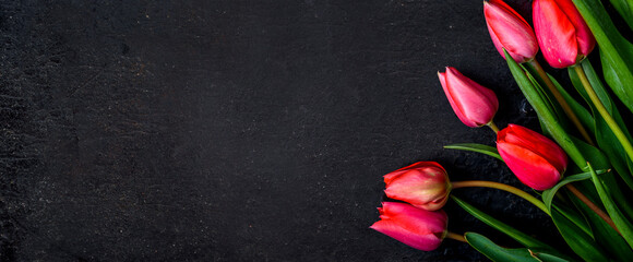 Red tulip flowers on black border background top view. Spring floral bouquet frame for mothers, wedding, valentine or woman holiday greeting card design.