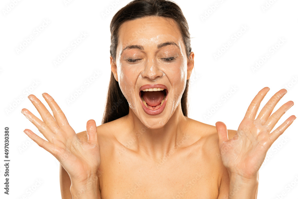 Portrait of a smiling woman with smeared makeup removing lotion on her face in a white background Portrait of a smiling woman with smeared makeup removing lotion on her face in a white background