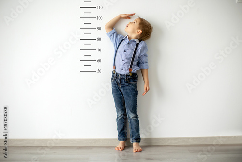 Canvas Print Little child, boy, measuring height against wall in room
