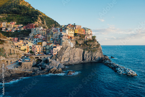 Fototapeta Naklejka Na Ścianę i Meble -  Beautiful view of rocky hills and colorful historic buildings of Manarola, tourist attraction and famous place in Liguria, Italy. Hillside over the sea at sunset.