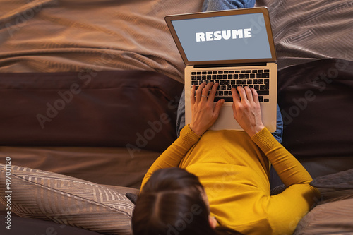 Tableau sur toile Back view of woman writing on laptop screen the word CV online, working from hom