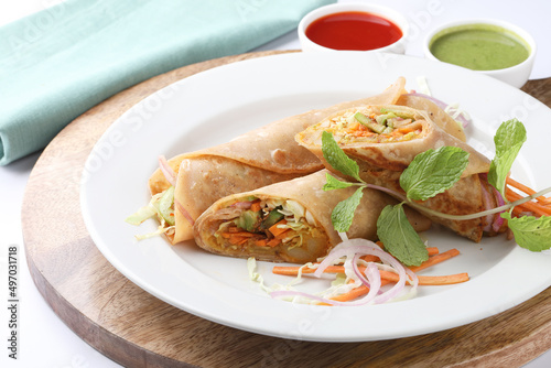 Indian Frankie Veg chapati Wrap / Kathi Roll, served in a plate with sauce & mint chutney. selective focus