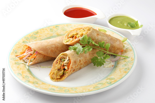 Indian Frankie Veg chapati Wrap / Kathi Roll, served in a plate with sauce & mint chutney. selective focus