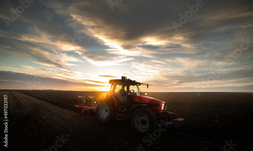 Fototapeta Naklejka Na Ścianę i Meble -  Tractor on the field during sunset.
