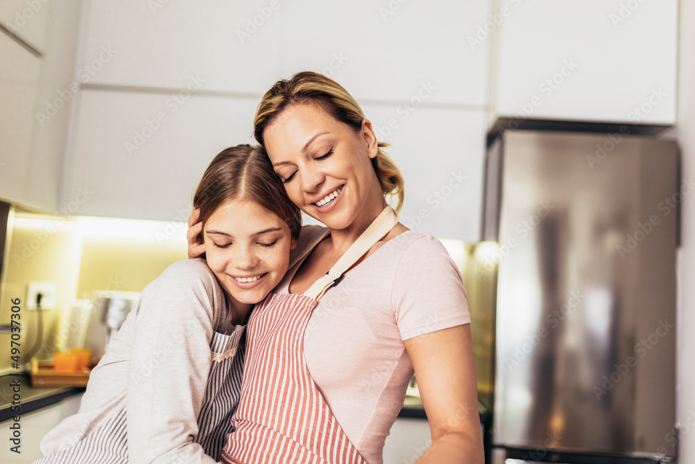 Smiling mother and daughter cooking together in the kitchen Smiling mother and daughter cooking together in the kitchen