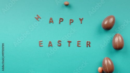 Easter chocolate eggs rolling on a yellow background