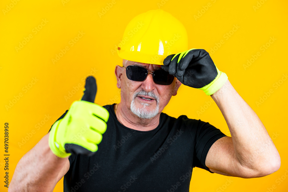 worker with gloves and helmet showing thumb up against yellow background