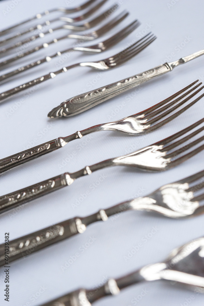 Old cutlery set lined up on a white background. Selective focus. Vintage forks, spoons, knifes. Old cutlery set lined up on a white background. Selective focus. Vintage forks, spoons, knifes.