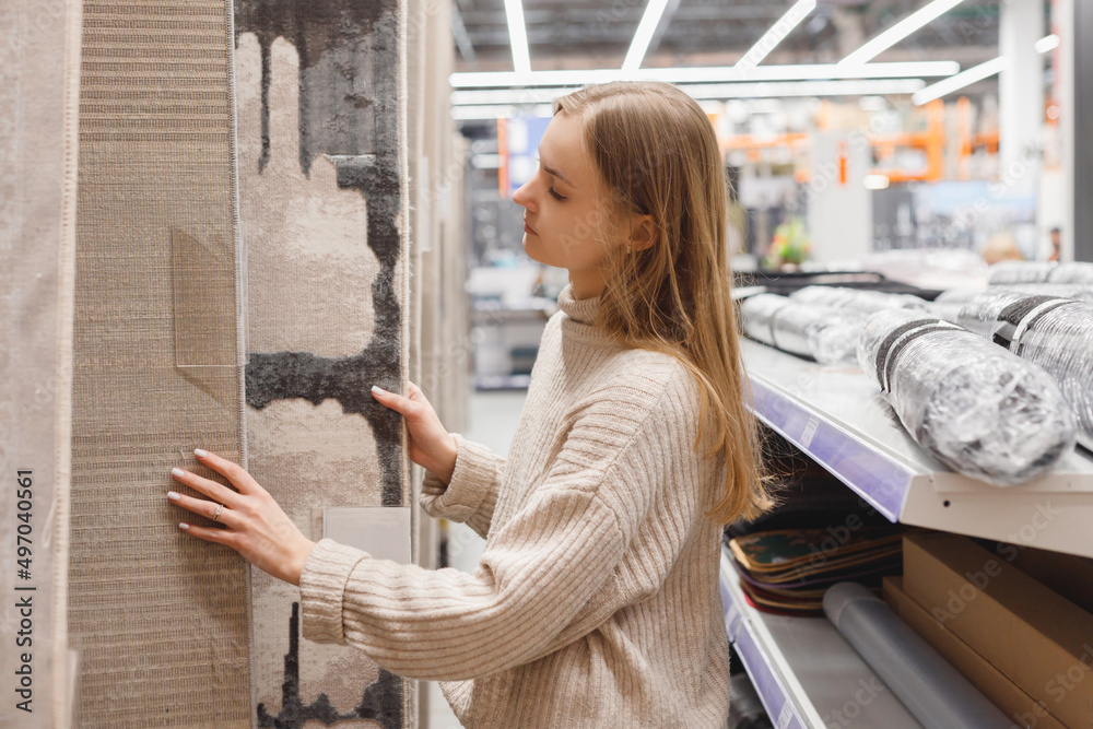 Young woman chooses a carpet in a furniture store