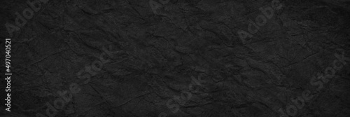 Abstract black background. Wide banner. Dark rock surface texture. Close-up. Stone rough background with copy space for design. Panoramic.