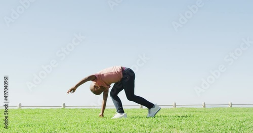 Video of happy african american boy doing cartwheel outdoors photo