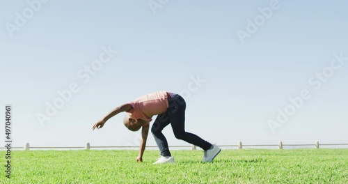 Video of happy african american boy doing cartwheel outdoors