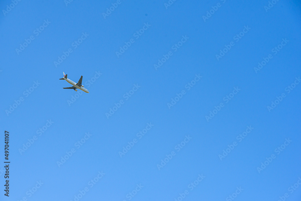 青空を飛ぶ飛行機のイメージ