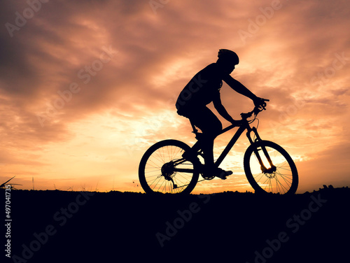 Silhouette of a male tourist and his bike, happiness and freedom. in the evening the light is beautiful