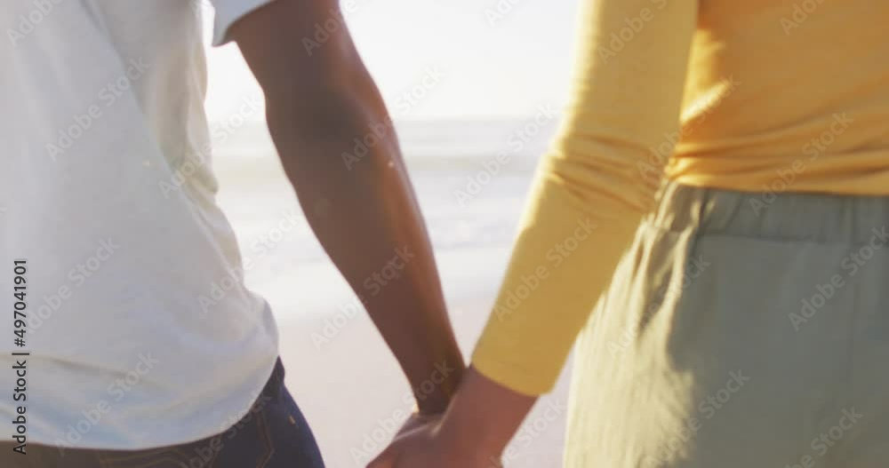 Smiling african american couple walking and holding hands on sunny beach Smiling african american couple walking and holding hands on sunny beach