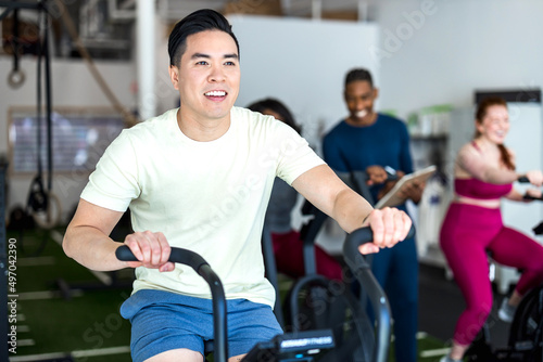 man riding exercise bike in spin class in gym, person riding gym a cycle ,young boy exercising on exercise bikes in gym