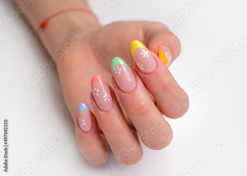 Hands of a young woman with a manicure. The nails are covered with gel polish with colored French and flowers