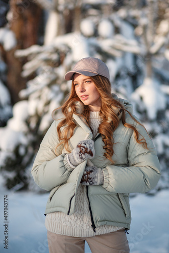 A model girl walking through a snow-covered forest, a demonstration of clothes.