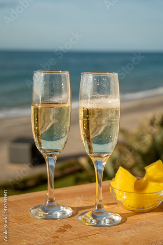 Outdoor breakfast with Spanish cava sparkling wine and pineapple with view on blue sea and sandy beach in Marbella, Costa del Sol vacation destination, Andalusia, Spain
