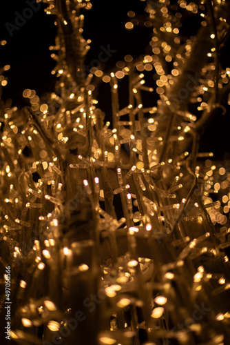 Lights in dark. Tree made of light bulbs. Christmas decorations in city. LEDs are yellow.