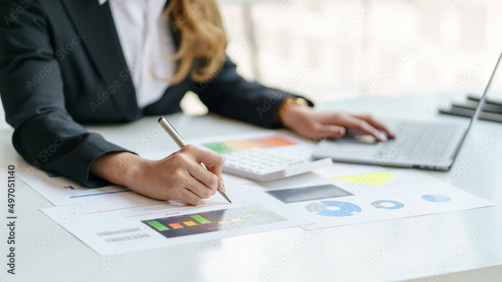 Close-up of business woman hands check company finances and earnings and budget with graph on desk in the office. Close-up of business woman hands check company finances and earnings and budget with graph on desk in the office.