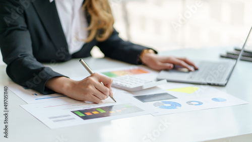 Close-up of business woman hands check company finances and earnings and budget with graph on desk in the office.