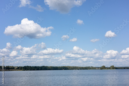 Summer countryside landscape with blue sky and calm water of river.