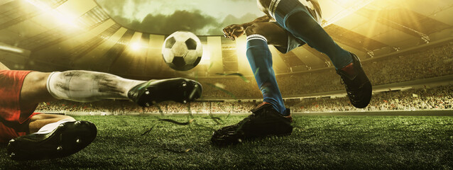 Close-up legs of soccer, football players in action, motion at the stadium with flashlights and crowded stands. Concept of sport, competition, movement, overcoming.