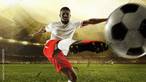 Professional soccer player in action at the stadium with flashlights hitting the ball for the winning goal  wide angle. Concept of sport  competition  movement  overcoming.