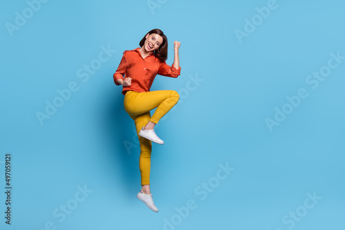 Full body profile side photo of young excited girl celebrate success fists hands triumph jump isolated over blue color background