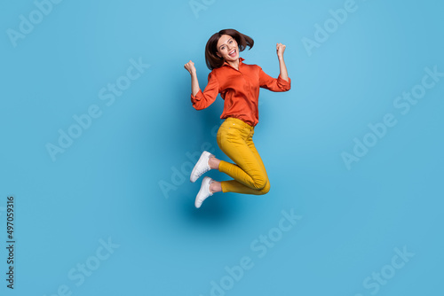 Full length body size view of attractive cheerful lucky slim girl jumping rejoicing isolated over bright blue color background