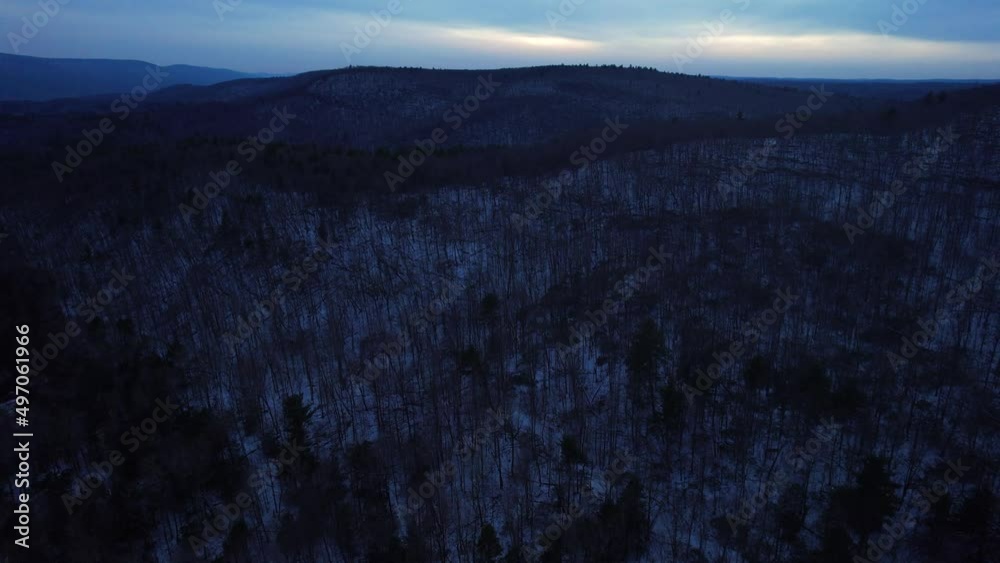 Aerial drone video footage of nightfall in the snowy appalachian mountains during winter, in the Catskill Mountains sub-range