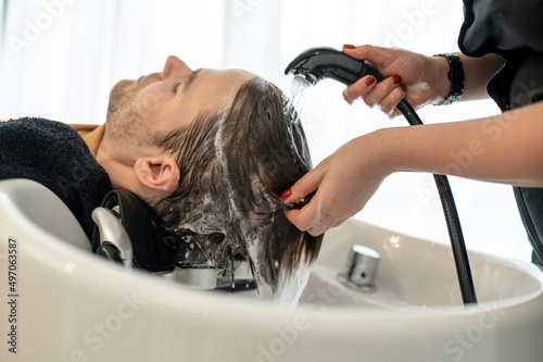 Beautician washing hair to the client and massaging his head
