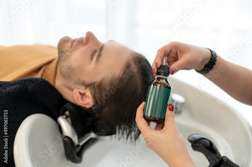 Beautician applying revitalizing hair drops to the clients head
