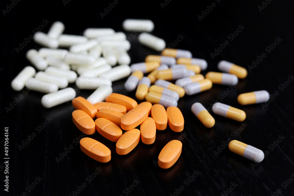 Different pills on a dark wooden table, medication in capsules. Concept of pharmacy, antibiotics, vitamins
