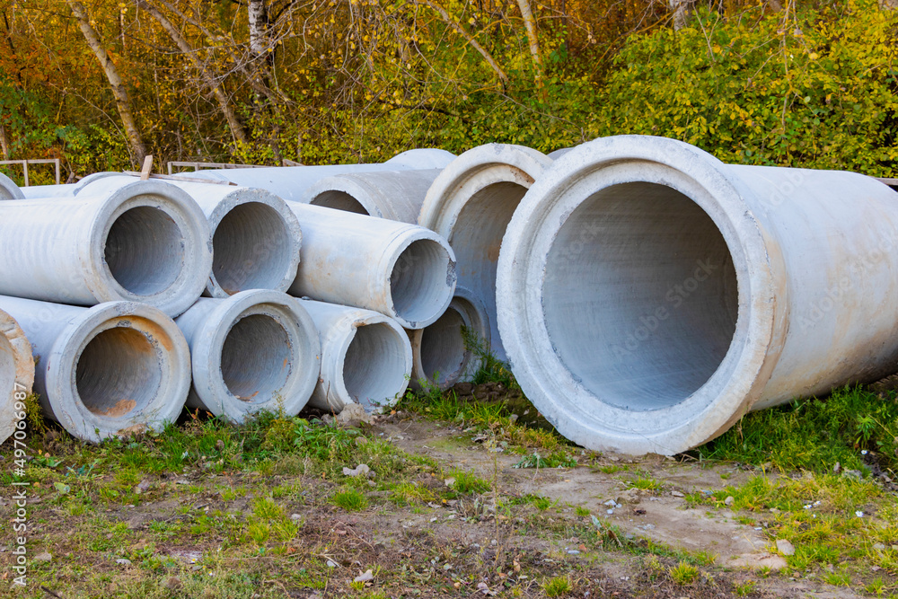 Reinforced concrete storm sewer pipes stacked at a construction site. Large diameter pipes.