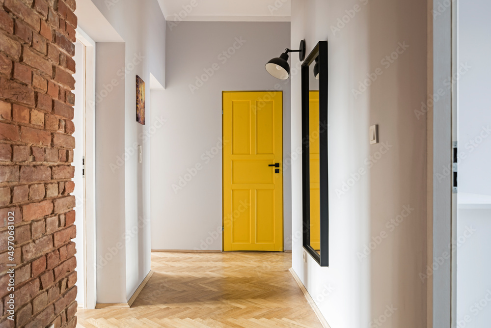 Fototapeta premium Przedpokój z ceglaną ścianą i dużym lustrem oraz żółtymi drzwiami